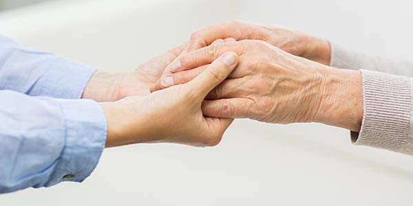 persona giovane che stringe le mani di una persona anziana
